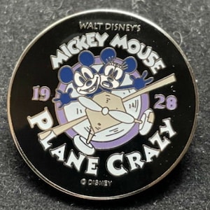 May include: Black and white pin featuring Mickey and Minnie Mouse in a plane. The text reads "Walt Disney's Mickey Mouse Plane Crazy 1928".