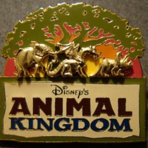 May include: A gold pin with a green tree, a red, orange, and yellow sunset, and a white banner with the text "Disney's Animal Kingdom".