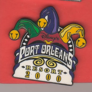May include: A colorful pin featuring a jester's hat with bells, the text "Disney's Port Orleans Resort 2000", and a Mickey Mouse head logo.