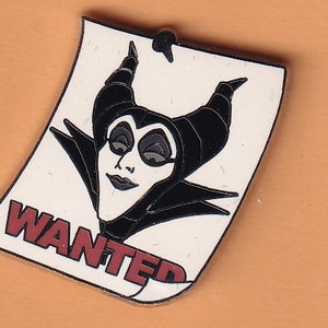 Op de afbeelding: Een witte poster met het woord "WANTED" in rood gedrukt. Een zwart-witte illustratie van Maleficent uit Disneys Doornroosje is op de poster.