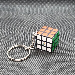 Peut inclure: Un porte-clés argenté avec un petit charme de Rubik's Cube noir, blanc, orange et vert.