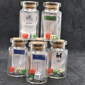May include: Six small glass bottles with cork stoppers, each containing miniature game pieces and property cards. The bottles include dice, houses, and hotels, with property names like Pennsylvania Avenue and Boardwalk. The theme is a miniature board game.
