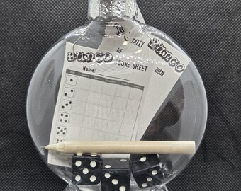 May include: Clear glass ornament containing a Bunco score sheet, a pencil, and three black dice with white dots. The ornament has a silver cap and a tag. The words "Bunco" and "Tally" are visible on the score sheet.