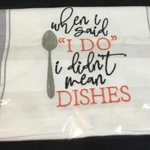 May include: White kitchen towel with gray stripes and the embroidered text "when I said 'I DO' I didn't mean DISHES". A gray spoon graphic is also included. The towel is packaged in clear plastic.