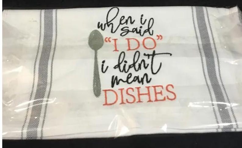 May include: White kitchen towel with gray stripes and the embroidered text "when I said 'I DO' I didn't mean DISHES". A gray spoon graphic is also included. The towel is packaged in clear plastic.