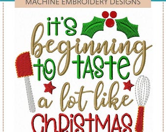 May include: A machine embroidery design featuring the text it's beginning to TASTE a lot like CHRISTMAS in green, gold, and red thread. The design includes a red spatula, a white whisk, green holly leaves, red berries, and two small red stars.