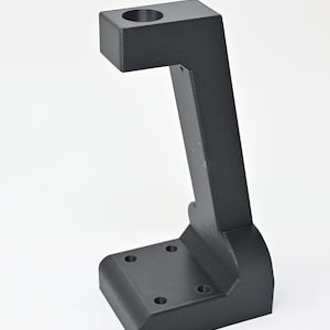 May include: A black plastic 3D printed stand with a round hole at the top and four screw holes on the base.