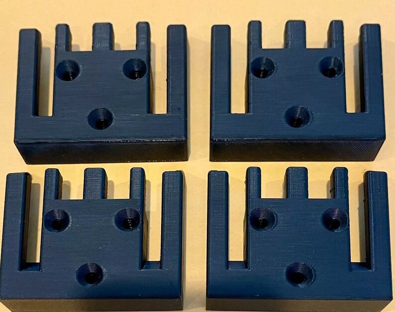 May include: Four black plastic 3D printed wall mounts with five slots each. The mounts have three screw holes on the back.