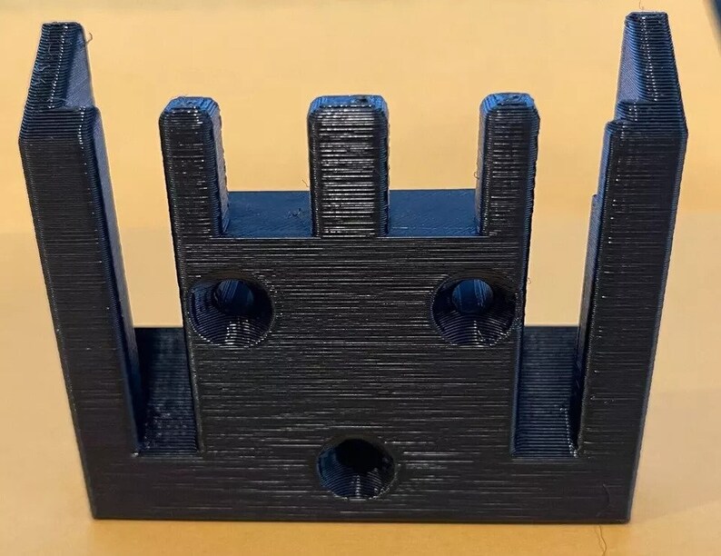 May include: Black plastic 3D printed wall mount with three slots and two holes.