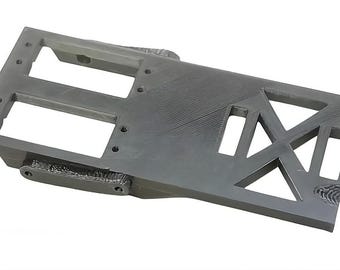 May include: A gray 3D printed plastic part with a rectangular shape and several cutouts. The part has a textured surface and appears to be a component for a larger assembly.