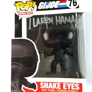 May include: A boxed Snake Eyes vinyl figure from the G.I. Joe Retro Toys Pop! series. The figure is black and has a gun. The box has the text "Snake Eyes" and "Larry Hama". The number 76 is on the top right.