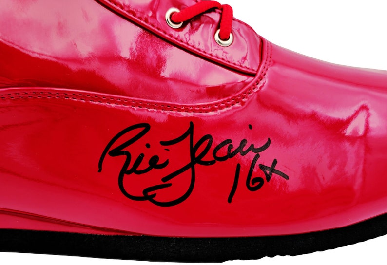 May include: A red patent leather boxing shoe with black laces and a black signature that reads "Ali Jean 16+ "