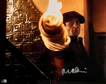 May include: A black and white photo of a man in a cap, holding a lit torch, with a signature below the image. The signature reads "Pacino."