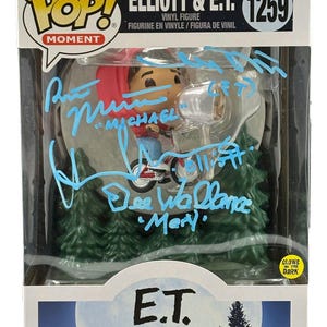 Könnte beinhalten: Funko Pop! Moment Vinylfigur von Elliott und E.T. auf einem Fahrrad, aus dem Film E.T. Der Außerirdische. Die Box enthält den Text "ELLIOTT & E.T. 1259" und leuchtet im Dunkeln. Die Box ist mit blauer Tinte signiert.