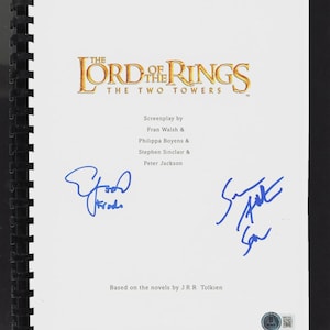 Puede incluir: Un guion encuadernado de "El Señor de los Anillos: Las Dos Torres" con el título de la película en letras doradas. El guion está firmado con tinta azul por dos personas. También es visible el texto "Guion de" y los nombres de los guionistas.