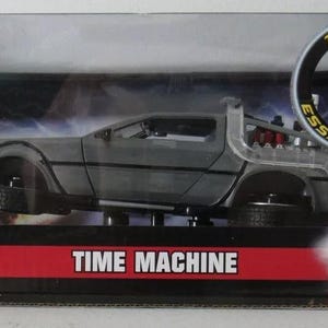 May include: A die-cast model of the DeLorean time machine from the movie Back to the Future II. The car is silver with a black interior and has the words "Time Machine" printed on the box. The box also has the words "Try Me!" and "Essai-Moi!" printed on it.