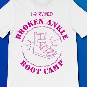 May include: A white t-shirt with a pink graphic design that says "I Survived Broken Ankle" with a drawing of a broken ankle boot. The text around the boot says "Neither swelling nor bruising nor plastic boots stays these sufferers in the swift completion of their anticipated recovery. Boot Camp."