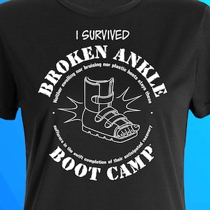 May include: Black t-shirt with a white graphic design that says "I Survived Broken Ankle" with a picture of a boot and the text "Boot Camp".