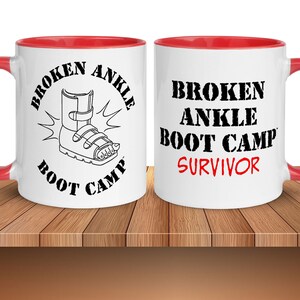 May include: White ceramic mug with a red rim. The mug has a black and white illustration of a broken ankle boot with the text "Broken Ankle Boot Camp" and "Survivor" in red.