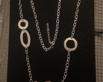 Long silver link chain decorated with open and solid silver shapes on the chain