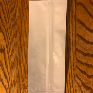 May include: A white stand-up pouch with a zipper closure. The pouch is made of a flexible, opaque material.