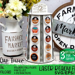 K&ouml;nnte beinhalten: Ein wei&szlig;er K-Cup-Kaffeepad-Turm mit mehreren Schlitzen, der verschiedene Kaffeepads enth&auml;lt. Der Turm hat ein Schild mit der Aufschrift "Coffee & Tea Bar, Fresh Brewed". Das Bild enth&auml;lt auch eine wei&szlig;e Vase im Bauernhausstil mit Blumen und ein Holzschild mit der Aufschrift "Farmer Market".