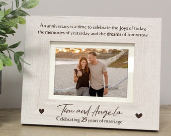 May include: White wooden picture frame with a quote about celebrating anniversaries. The frame has a photo of a couple on a beach and the text "Tim and Angela Celebrating 25 years of marriage".
