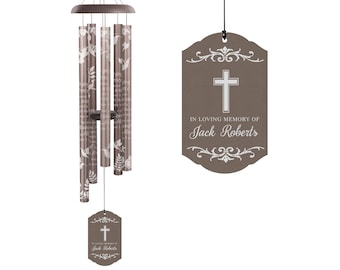May include: A brown wind chime with a white cross and the text "In loving memory of Jack Roberts" on a brown tag. The wind chime has a floral design with white hummingbirds.