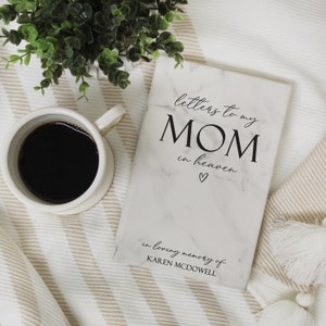 May include: A white marble-patterned journal with the text "letters to my MOM in heaven" and a small heart symbol. The text "in loving memory of KAREN MCDOWELL" is at the bottom of the journal.