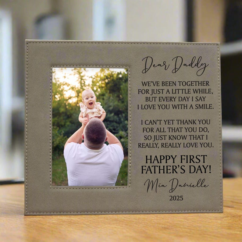 First Father's Day Picture Frame with "Dear Daddy" Poem and personalized with baby's name in tan sitting on a table inside a home