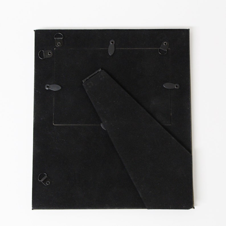 May include: Black picture frame with a stand on the back. The frame has a black mat and is made of wood.