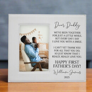 First Father's Day Picture Frame with "Dear Daddy" Poem and personalized with baby's name in white on a wooden table