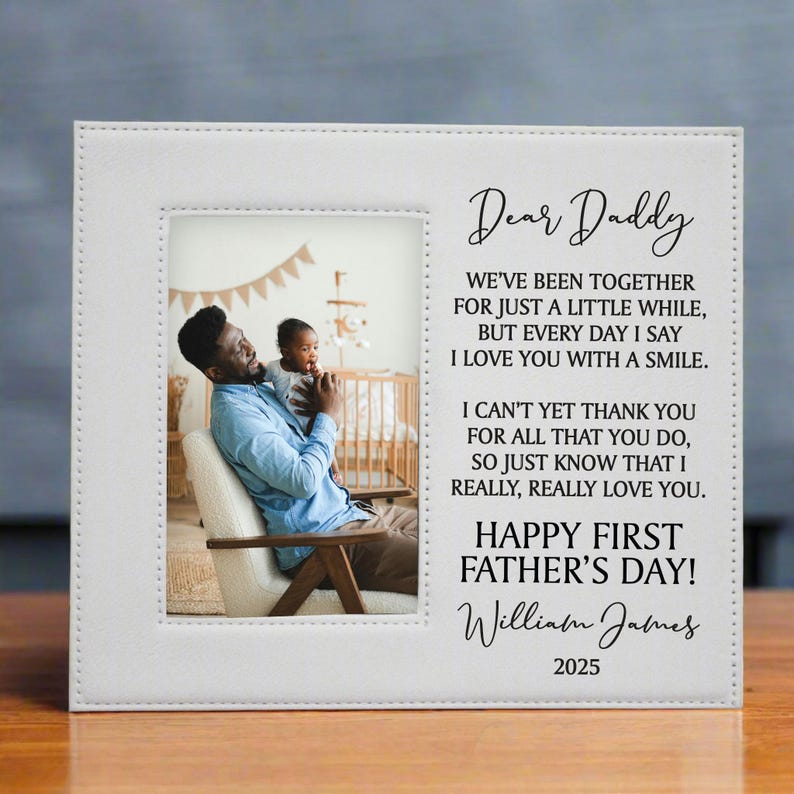 First Father's Day Picture Frame with "Dear Daddy" Poem and personalized with baby's name in white on a wooden table