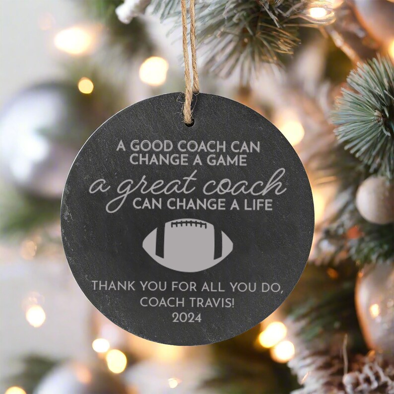 May include: Black and white round ornament with a football design and the text "A good coach can change a game, a great coach can change a life. Thank you for all you do, Coach Travis! 2024."