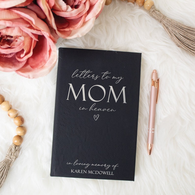 May include: A black leather-bound journal with the text "letters to my MOM in heaven" and a small heart symbol. The journal also has the text "in loving memory of KAREN MCDOWELL" on the bottom.