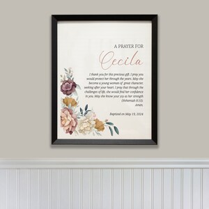 May include: A framed print with a floral design and a prayer for Cecila. The text reads "A Prayer for Cecila. I thank you for this precious gift. I pray you would protect her through the years. May she become a young woman of great character, seeking after your heart. I pray that through the challenges of life, she would find her confidence in you. May she know your joy as her strength (Nehemiah 8:10). Amen. Baptized on May 19, 2024."