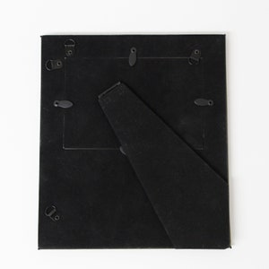Peut inclure: Cadre photo noir avec un support au dos. Le cadre a un passe-partout noir et est en bois.