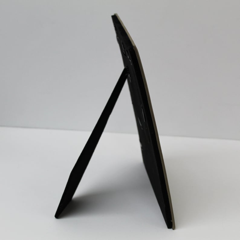 May include: A black picture frame with a stand on the back. The frame is made of a sturdy material and has a simple design.