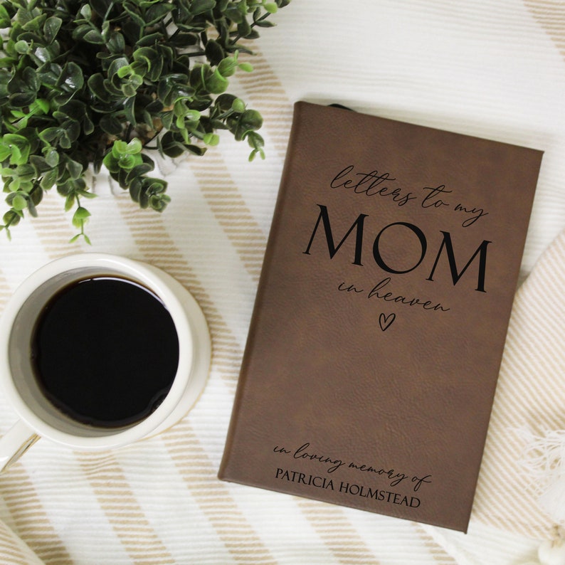 May include: A brown leather-bound journal with the text "letters to my MOM in heaven" and a heart symbol. The journal also has the text "in loving memory of PATRICIA HOLMSTEAD" on the bottom.