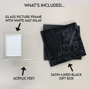 K&ouml;nnte beinhalten: Ein Bilderrahmen aus Glas mit einem wei&szlig;en Passepartout, Acrylf&uuml;&szlig;en und einer schwarzen Geschenkbox mit Satin-Futter. "WHAT'S INCLUDED..." steht oben im Bild.