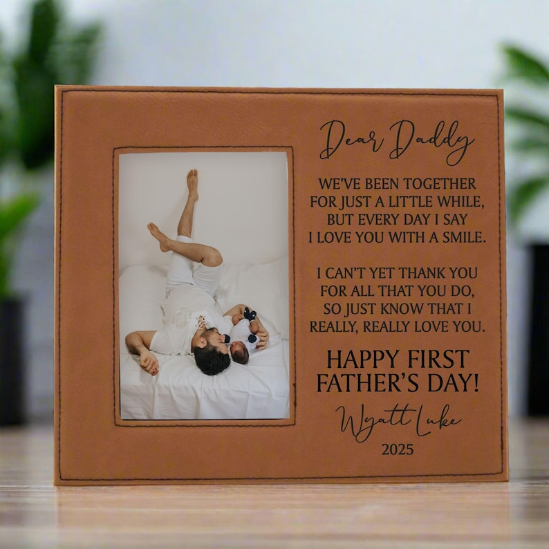 First Father's Day Picture Frame with "Dear Daddy" Poem and personalized with baby's name in carmel brown sitting on a table with plants in the background