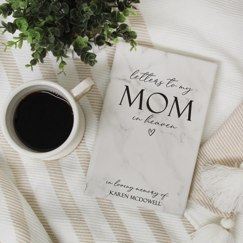 May include: A white marble-patterned journal with the text "letters to my MOM in heaven" and a small heart symbol. The text "in loving memory of KAREN MCDOWELL" is at the bottom of the journal.