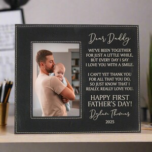 First Father's Day Picture Frame with "Dear Daddy" Poem and personalized with baby's name in black sitting on a desk
