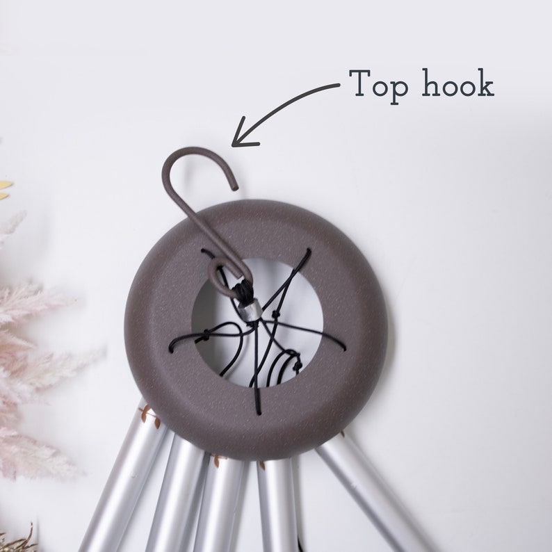 May include: A gray metal wind chime with a top hook. The chime has six aluminum tubes and a round, gray metal top with a black string.