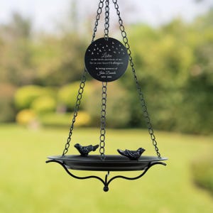 May include: Black metal bird feeder with a round plaque that reads "Listen to the birds and think of me for in your heart I'll always be. In loving memory of John Daniels 1978-2024".