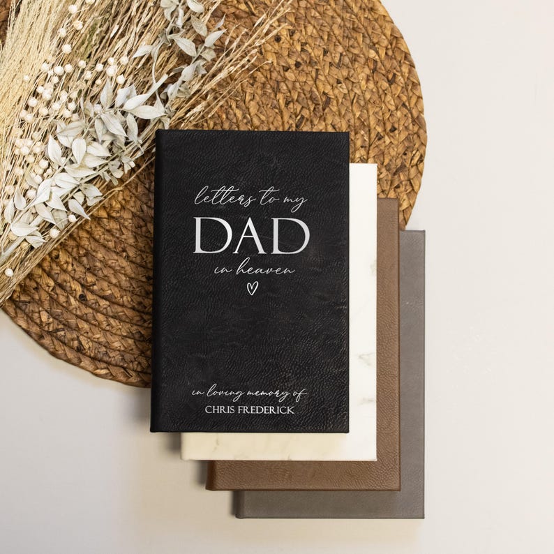 Może przedstawiać: Czarny, sk&oacute;rzany dziennik z tekstem "letters to my DAD in heaven" i małym symbolem serca. Na dole dziennika widnieje napis "in loving memory of CHRIS FREDERICK".