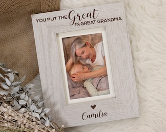 May include: A light gray wooden picture frame with the text "YOU PUT THE Great IN GREAT GRANDMA" and the name "Camila" below a heart. The frame holds a photo of a woman and a child.