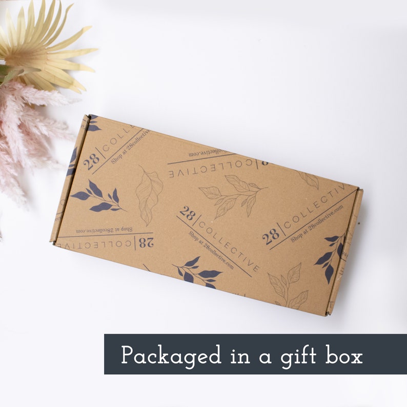 May include: A brown cardboard box with a white background. The box is decorated with a repeating pattern of leaves and the text "28|COLLECTIVE Shop at 28collective.com".