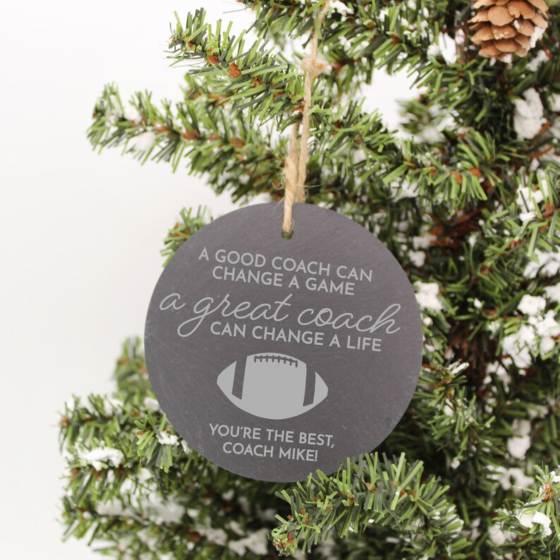 May include: A black slate ornament with a white inscription that reads "A good coach can change a game, a great coach can change a life. You're the best, Coach Mike!"  A gray football graphic is included in the design.