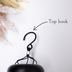 Peut inclure: Gros plan sur un crochet en m&eacute;tal noir avec un design incurv&eacute;. Le crochet est fix&eacute; &agrave; un objet noir avec un accent argent&eacute;. Les mots "Top hook" sont &eacute;crits au-dessus du crochet.